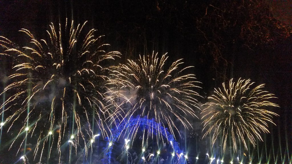 A fireworks display over the London Eye. The London Eye is lit up with bright blue lights.